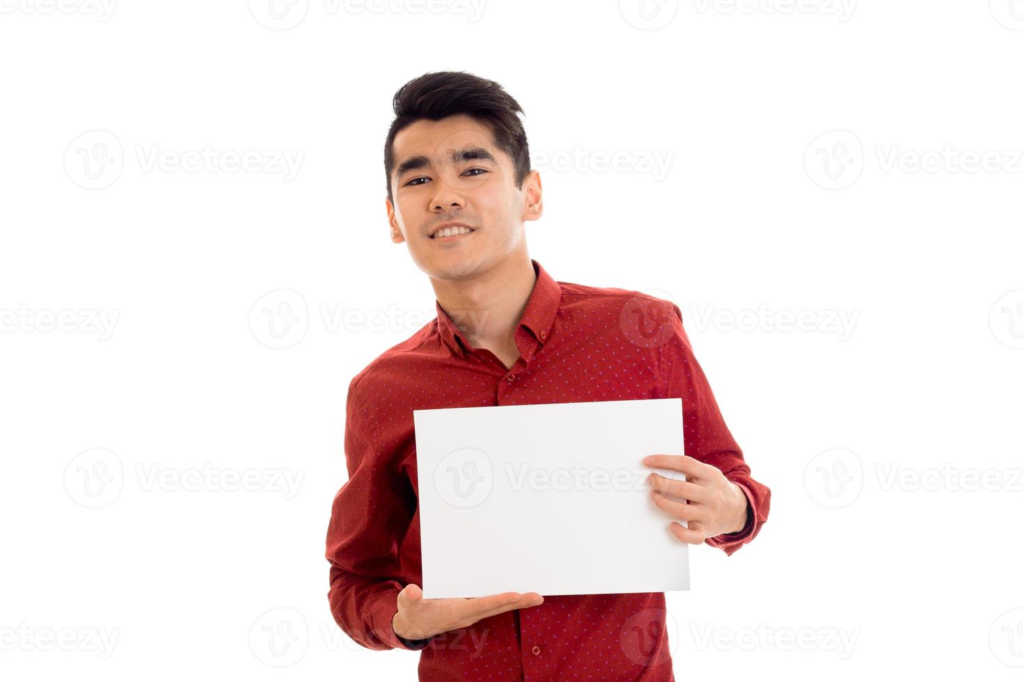 ung Lycklig brunett man i röd t-shirt Framställ med vit plakat isolera på bakgrund foto