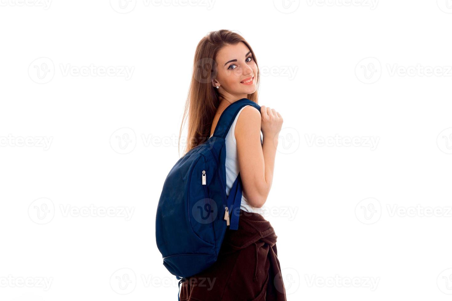 Lycklig ung studenter flicka med blå ryggsäck på axel leende på kamera isolerat på vit bakgrund foto