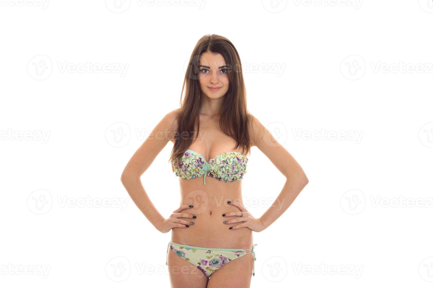 förtjusande ung kvinna med stor naturlig bröst i baddräkt med blommig mönster ser på de kamera och leende isolerat på vit bakgrund foto