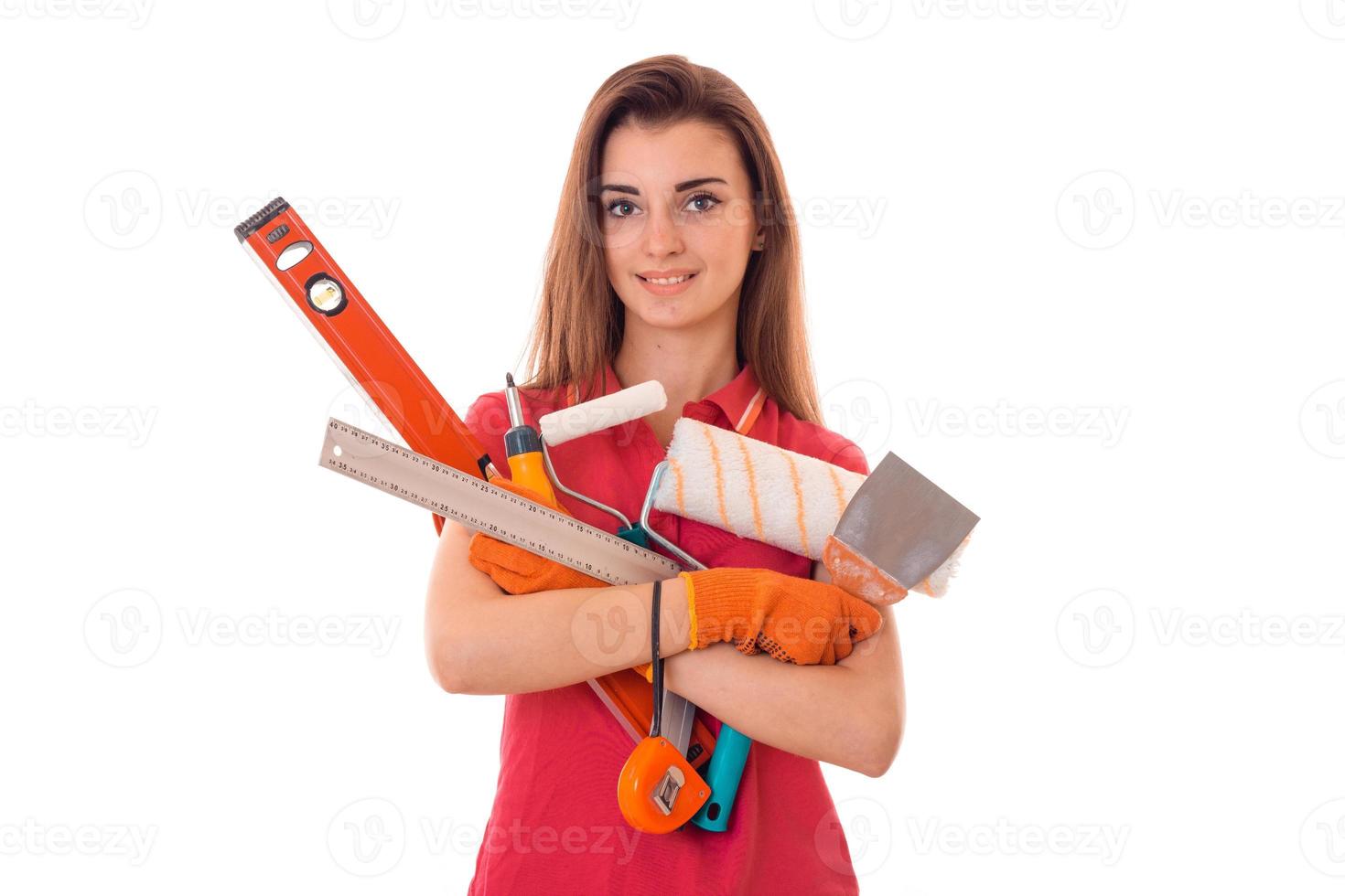 attraktiv ung smal byggare flicka gör renoveringar med verktyg i henne händer isolerat på vit bakgrund foto