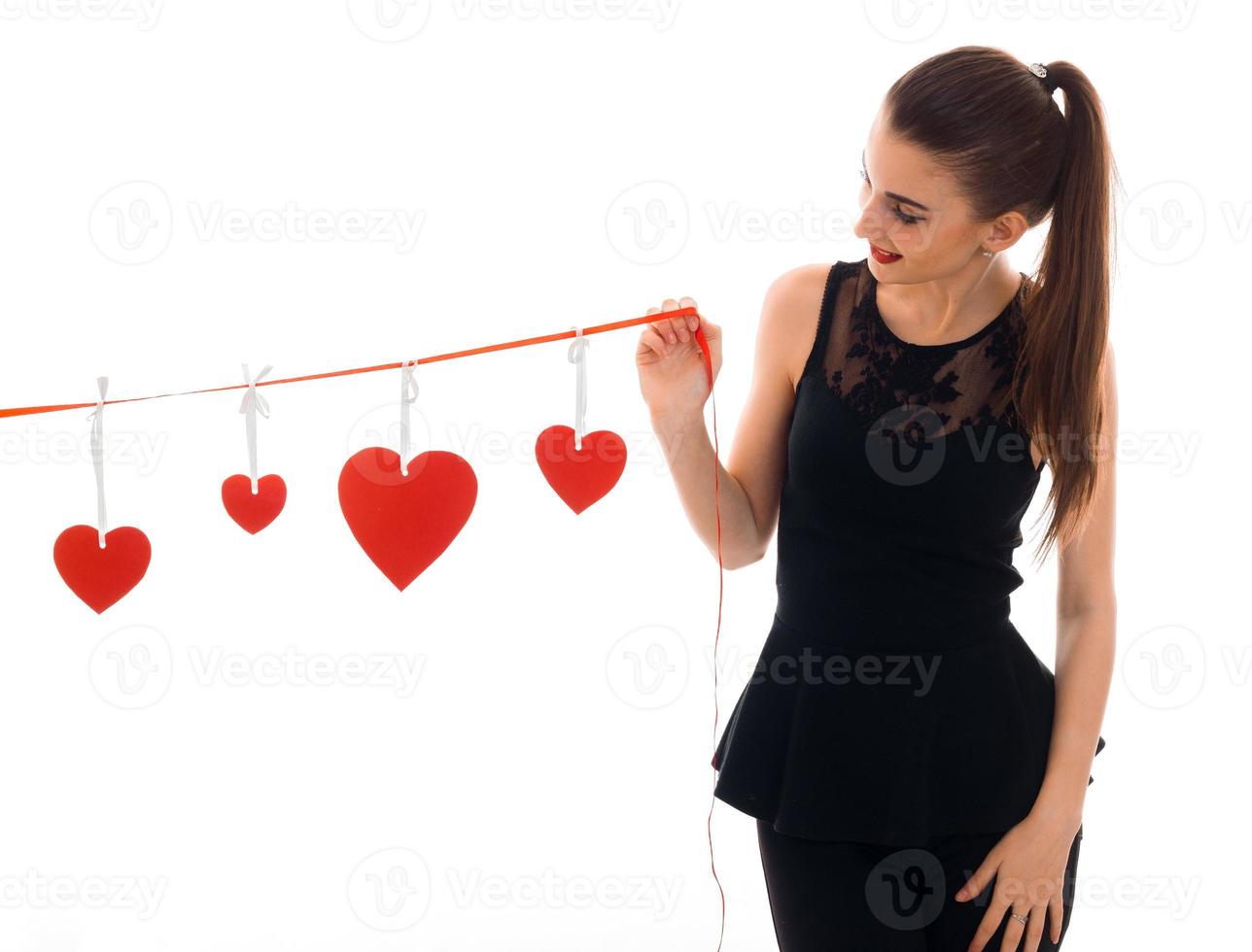 en ung flicka i en svart klänning innehav en band med hjärtan foto