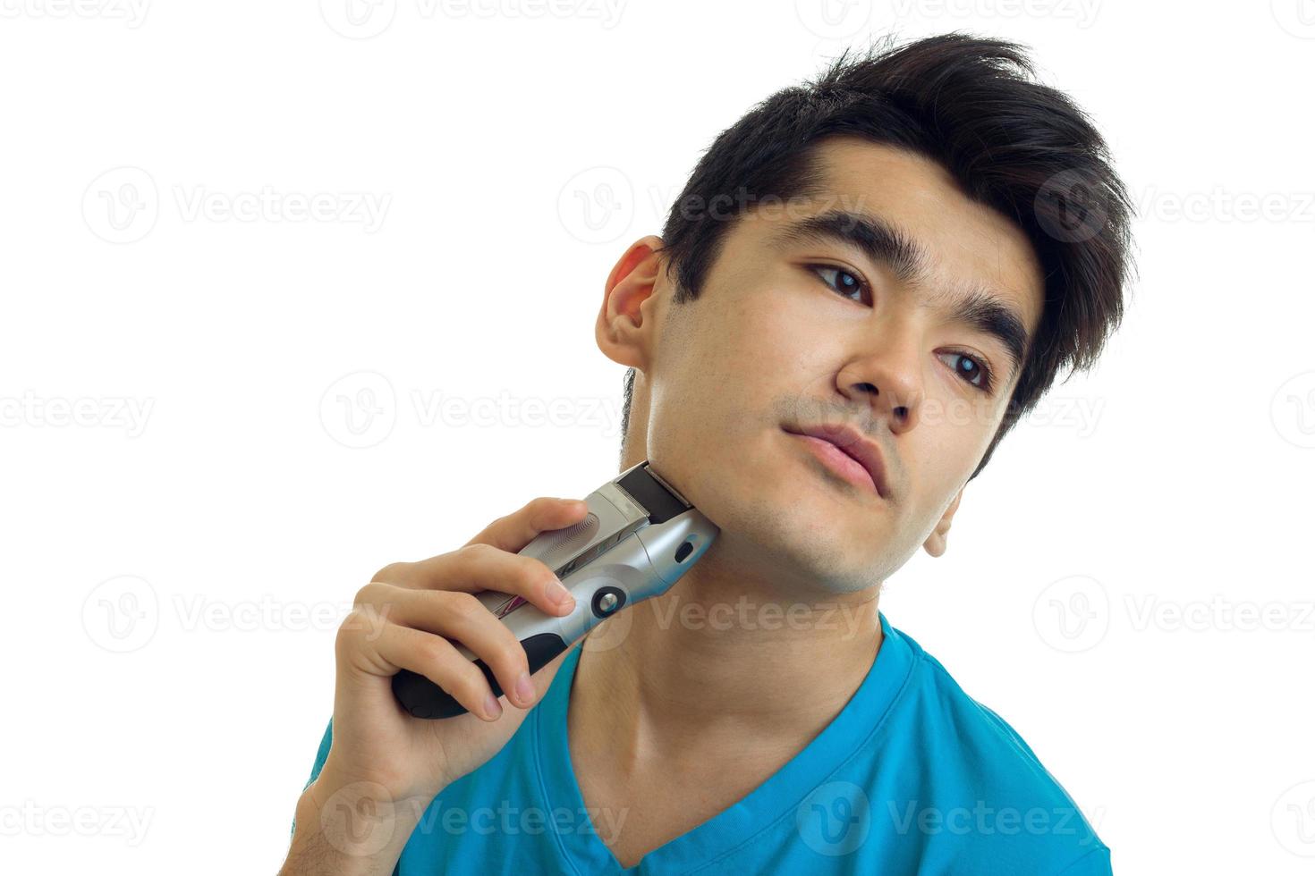 av en stilig ung man med svart hår och rakar hans huvud lutande hans ansikte maskin närbild foto