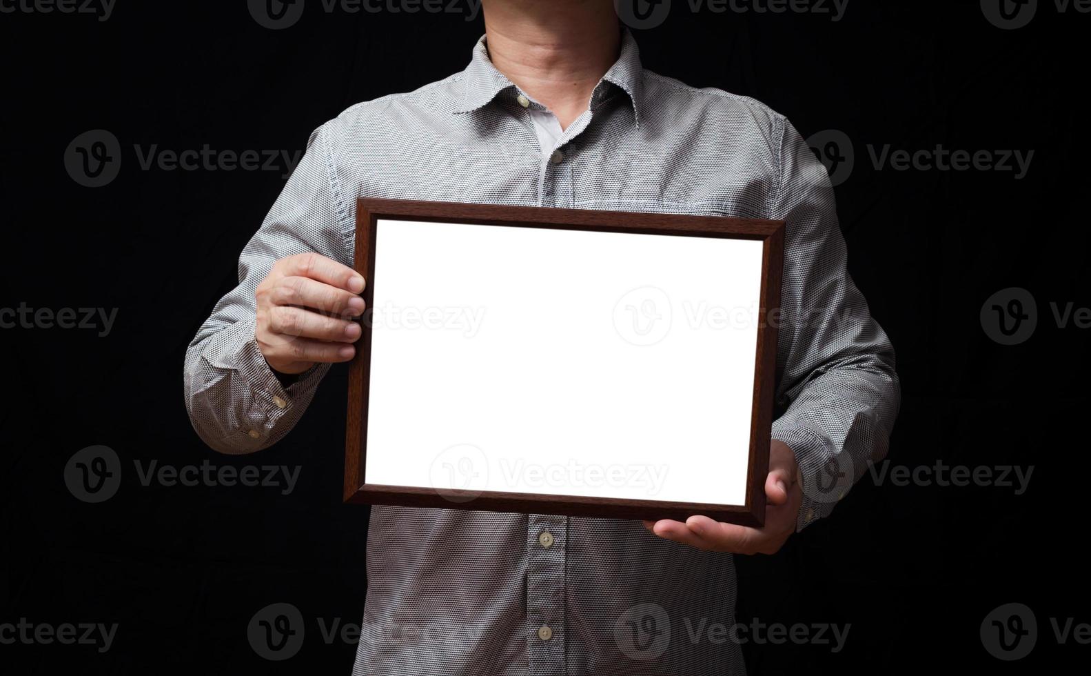 en tom diplom eller en attrapp certifikat i de hand av en man anställd bär en skjorta på svart bakgrund. de horisontell bild ram är tömma och de kopia Plats. foto