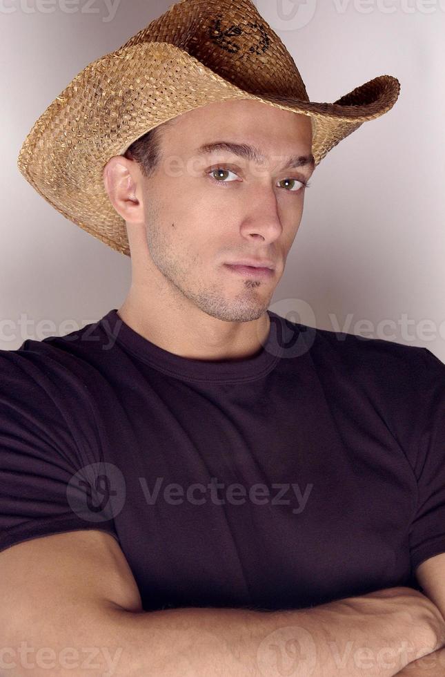 en stilig cowboy bär en cowboy hatt i en mörk skjorta i en studio porträtt ser varm och sexig. foto