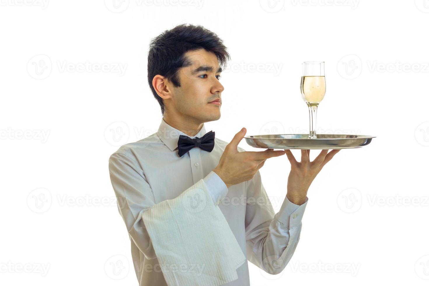 fantastisk smal ung servitör Uppfostrad hans händer i en bricka med en glas av champagne foto