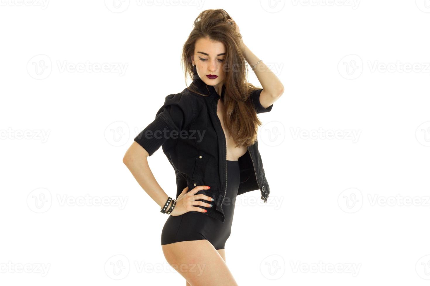 ung skön flicka i svart klänning innehav hand hår och Framställ i de studio foto