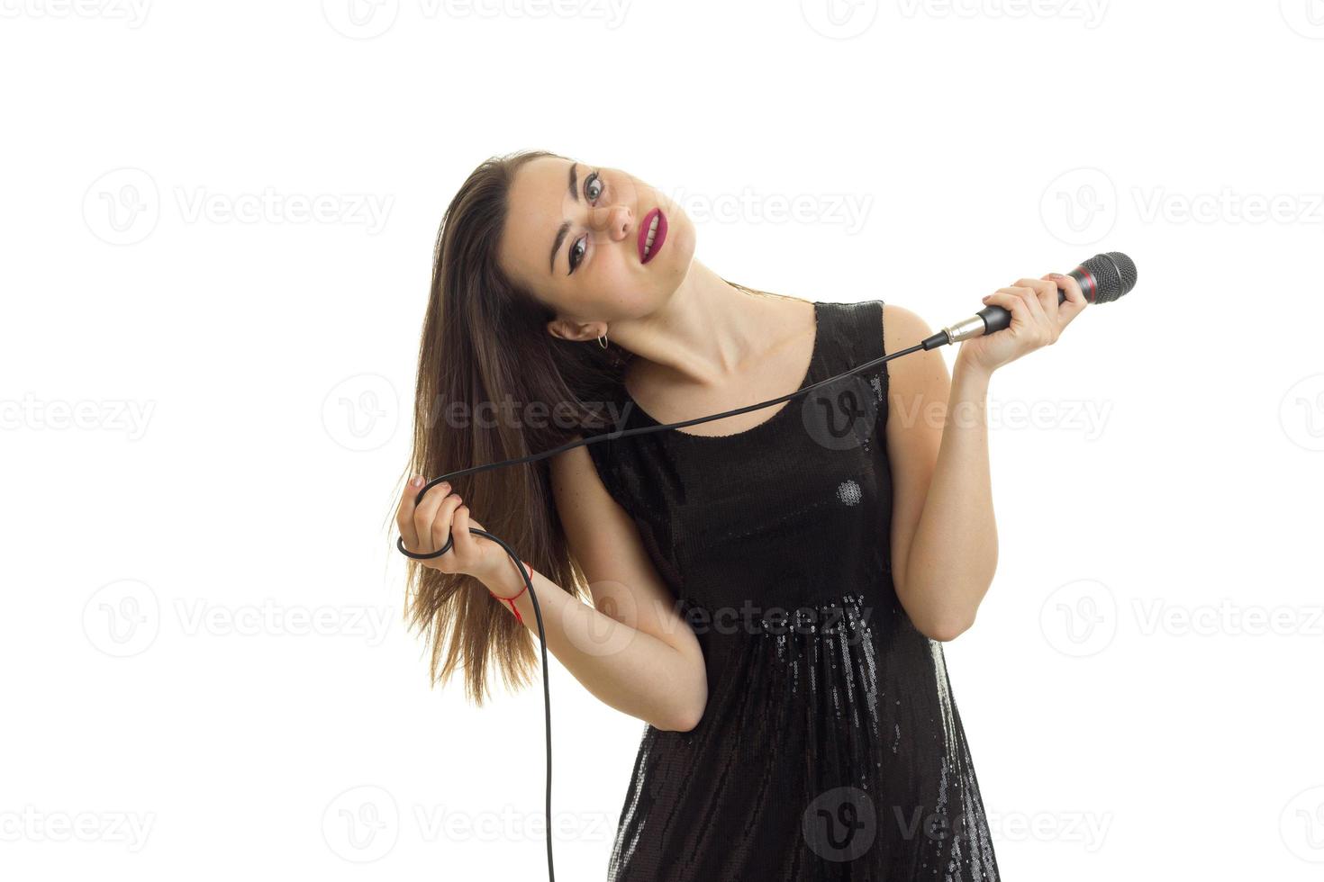 horisontell porträtt av charmig ung sångare med en mikrofon i henne hand foto