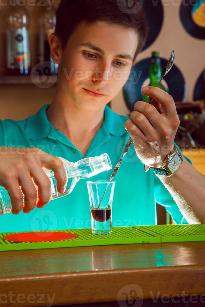 bartender häller en andra lager av alkohol i en kort cocktail foto