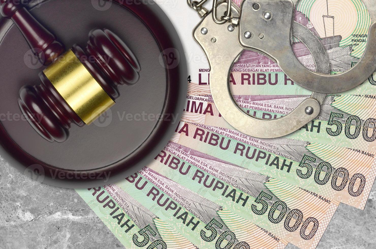 5000 indonesiska rupiah räkningar och bedöma hammare med polis handklovar på domstol skrivbord. begrepp av rättslig rättegång eller bestickning. beskatta undvikande foto
