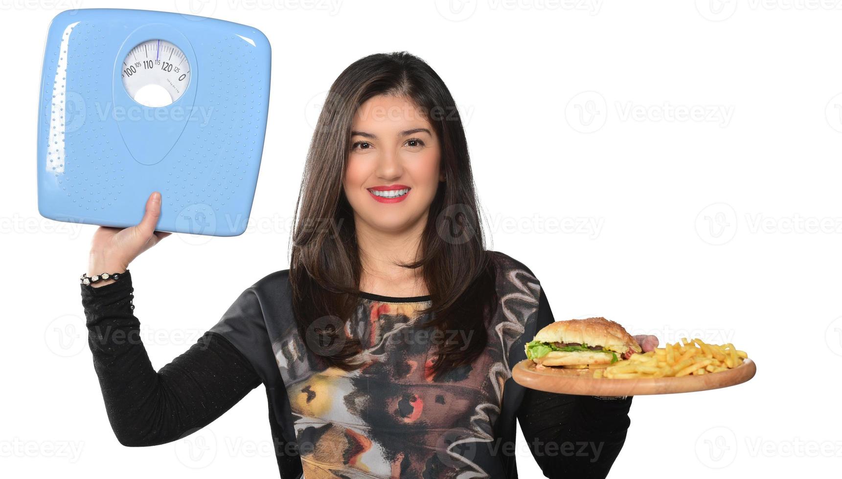 porträtt av en skön rolig ung flicka på de vit bakgrund, innehav en bricka burger med hamburgare och mätning skala foto