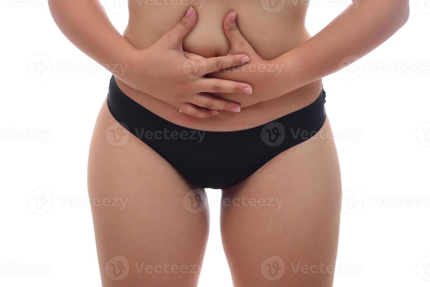 ung skön kvinna lidande från smärta i henne mage ser hjälplös på isolerat vit bakgrund, sjukvård begrepp foto