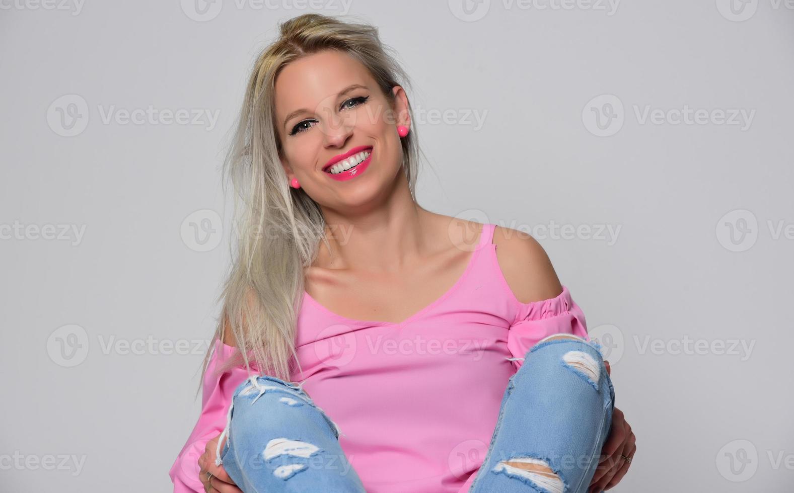 porträtt av skön ung kvinna i söt rosa skjorta och blå jeans Framställ i studio. begrepp av skönhet, känslor, ansiktsbehandling uttryck, livsstil, mode, ungdom kultur foto