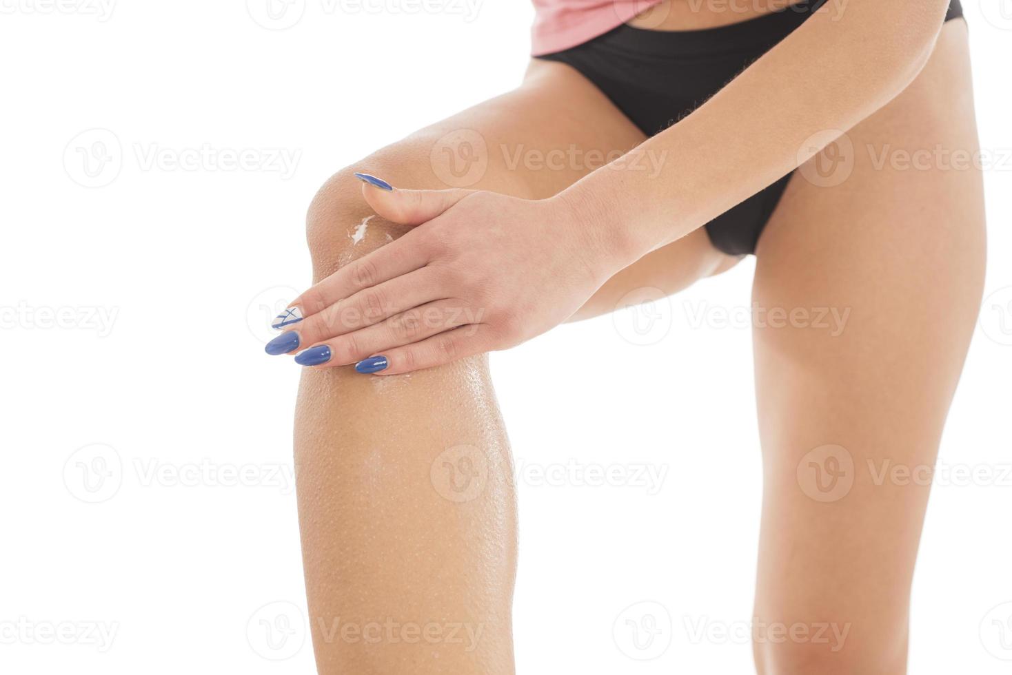 kropp vård. okänd kvinna applicering grädde på ben. kvinna applicering anti celluliter grädde foto