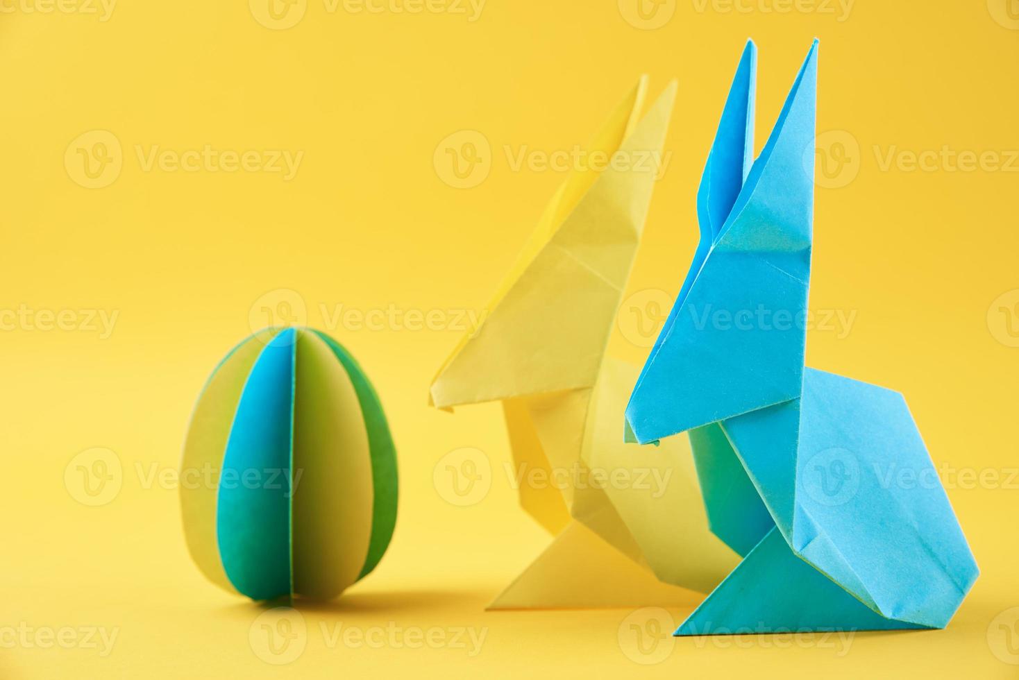 två papper origami esater kaniner och färgad ägg på gul bakgrund foto