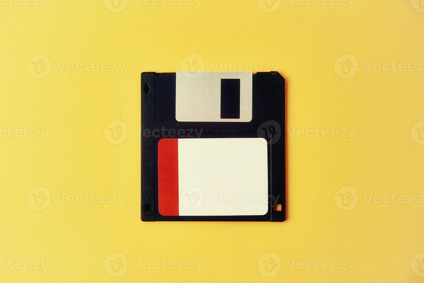 svart diskett diskett på gul bakgrund. årgång dator diskett, närbild foto