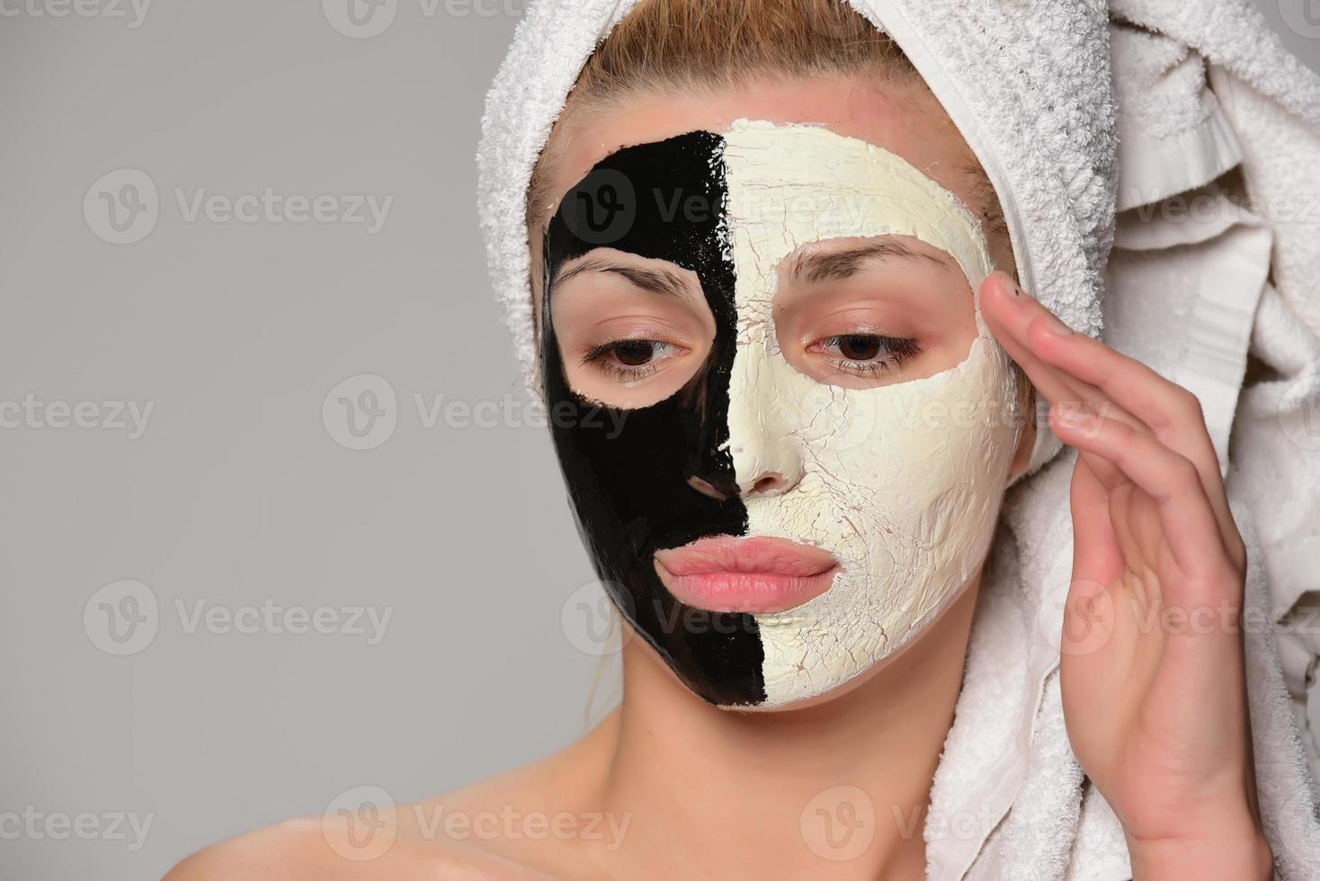 skön kvinna modell med svart och vit ansiktsbehandling kosmetisk mask foto