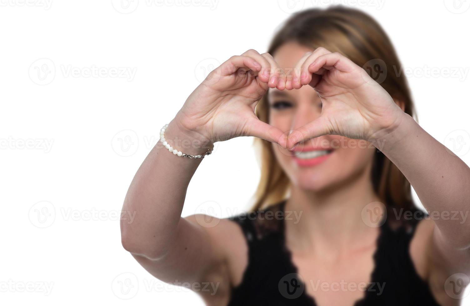 porträtt av en ung kvinna framställning en hjärta gest med henne händer foto