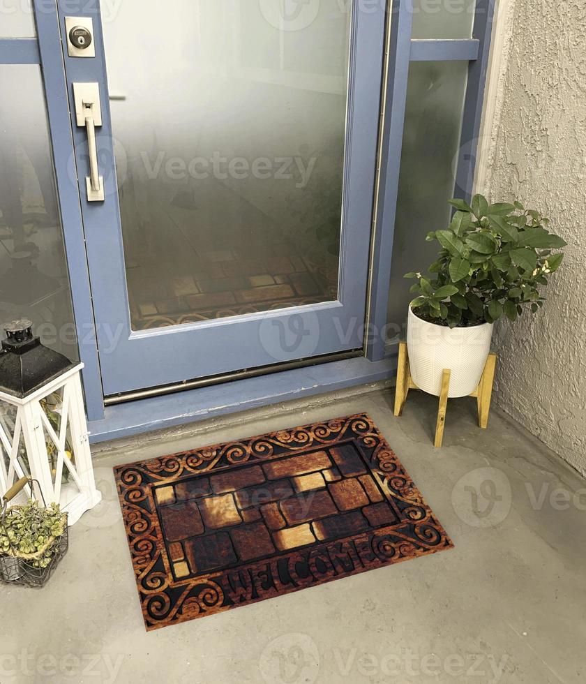 designer Välkommen inträde dörrmatta placerad utanför inträde dörr med växt och lampa foto