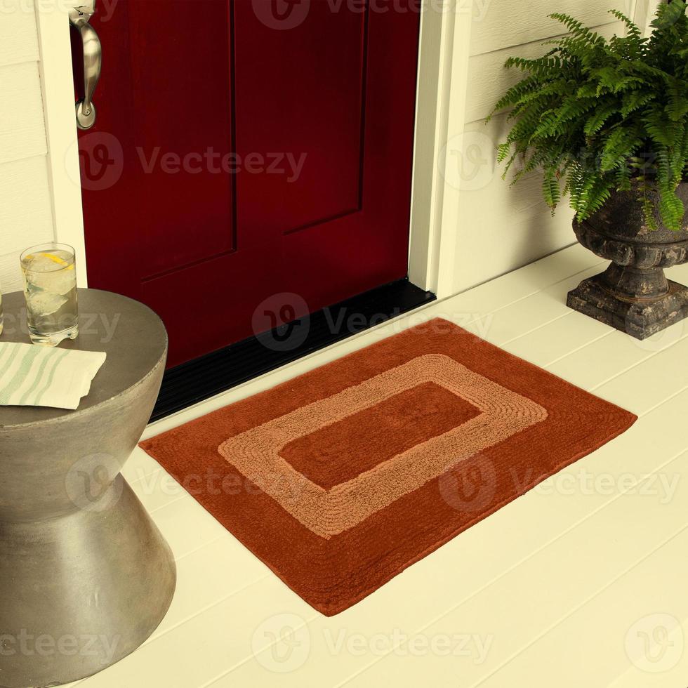 designer Välkommen inträde dörrmatta placerad på golv utanför inträde dörr med växter och citron- is dryck foto