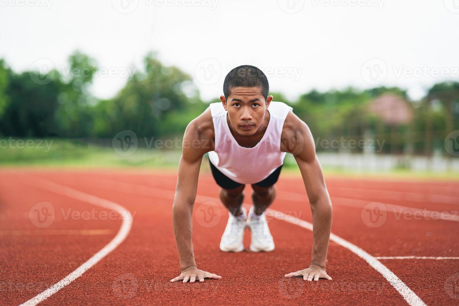 idrottare sport man löpare bär vit sportkläder till skjuta på upp, stretching och värma upp innan praktiserande på en löpning Spår på en stadion. idrottare sportman förbereda till Träning för konkurrens lopp. foto