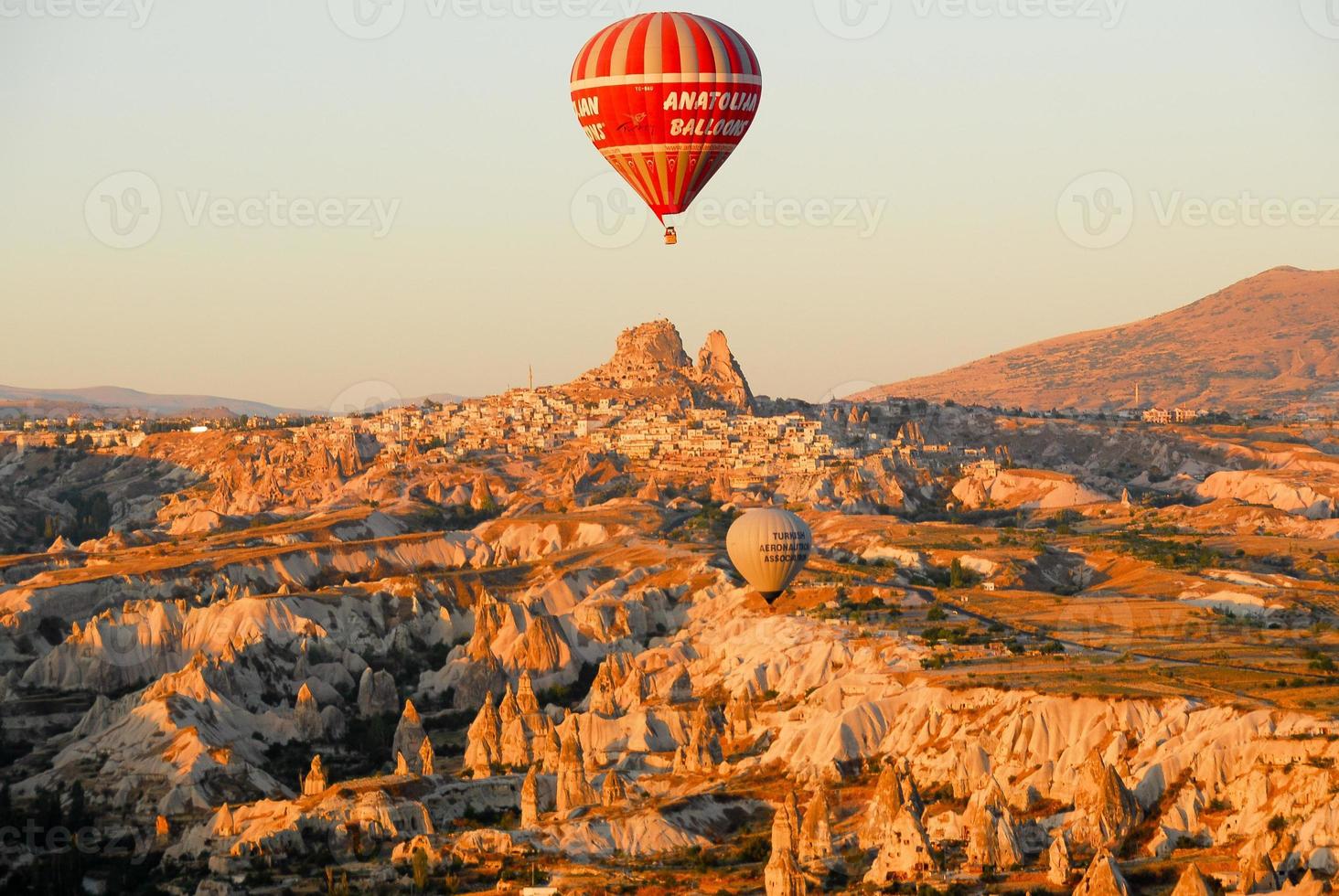 goreme, Kalkon - september 21, 2007 - varm luft ballong stigande över goreme by, Kalkon på soluppgång. lantlig cappadocia landskap. sten hus i goreme, Kappadokien. landsbygden livsstil. foto