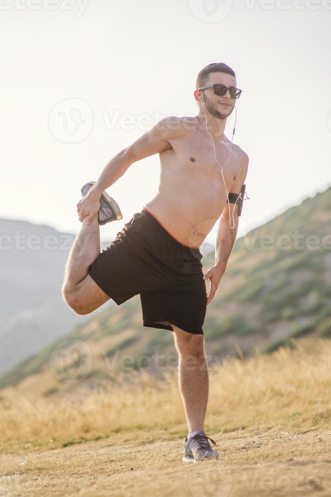 atletisk ung man stretching efter springa i de natur. sport begrepp foto