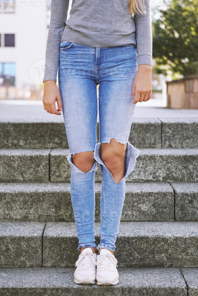 bedrövad denim rev jeans med hål exponera knän av flicka foto