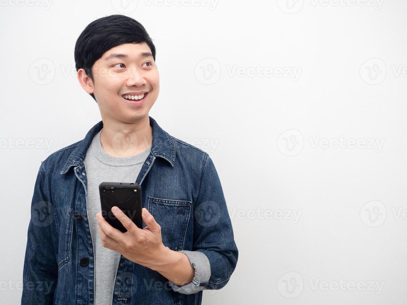 asiatisk man jeans kostym leende innehav mobil telefon ser på kopia Plats porträtt foto