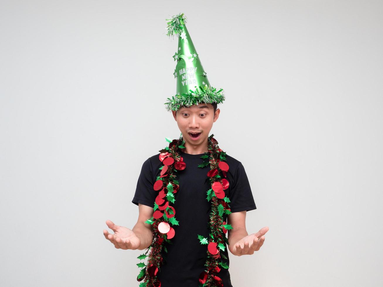 ung asiatisk man svart skjorta med grön hatt och tofs färgrik glad på ansikte hand upp och se ner på hand säga Wow på vit isolerat bakgrund foto