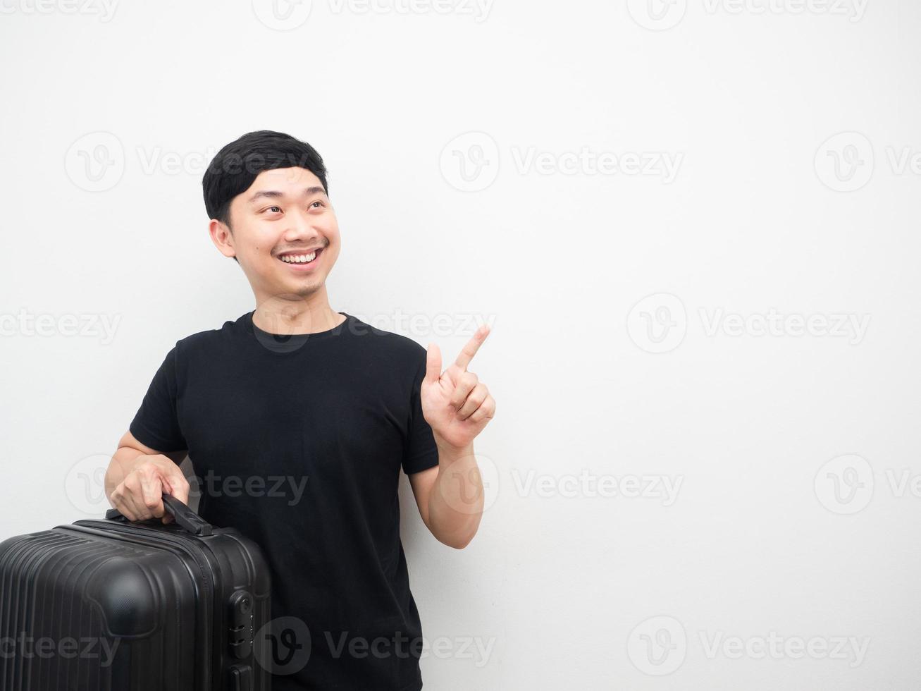 man innehav bagage leende och punkt finger på kopia Plats foto