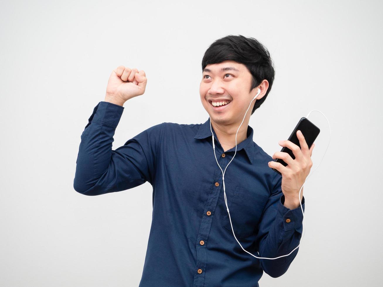 asiatisk man lyssnande musik förbi hörlur innehav mobiltelefon och dans roligt i Lycklig känsla foto