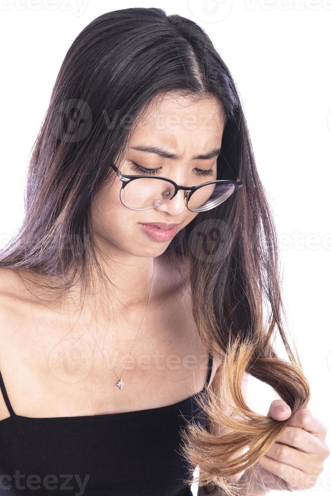 porträtt av skön ledsen ung kvinna med lång hår i hand. närbild av olycklig kvinna modell ser på dela slutade hår. hår vård begrepp foto