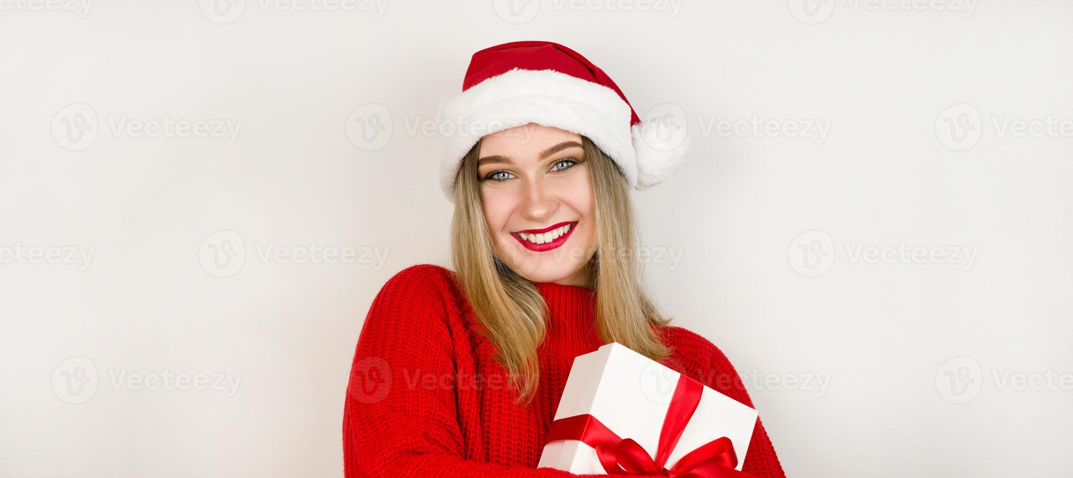 jul baner med plats för text med Söt flicka i santa hatt och röd Tröja innehav gåva mot vit bakgrund foto