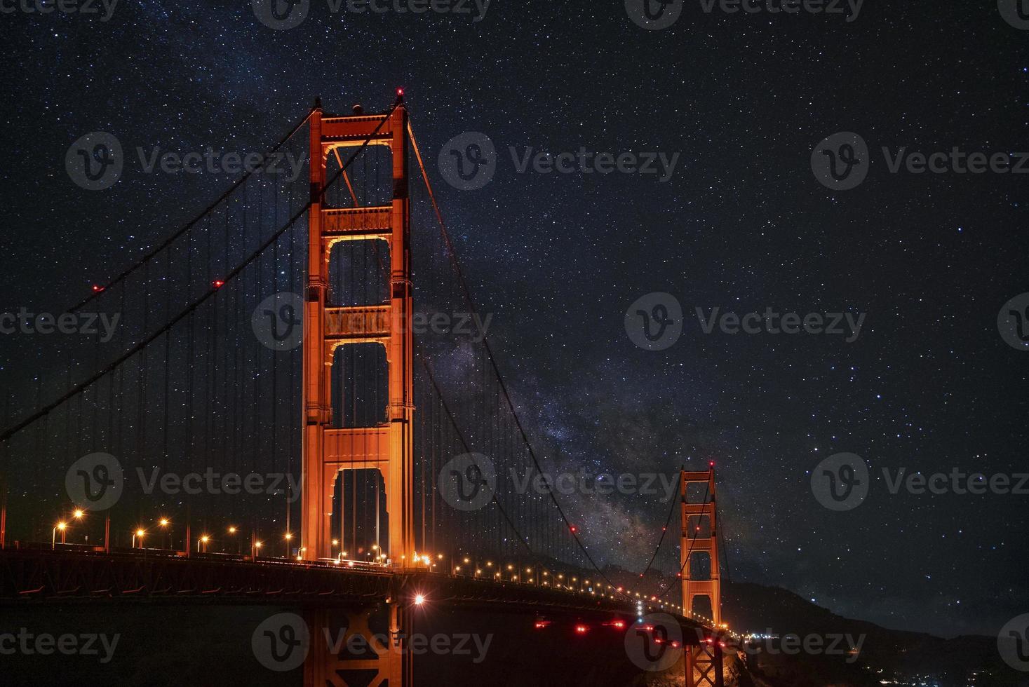 upplyst gyllene Port suspension bro under skön stjärna fält på natt foto