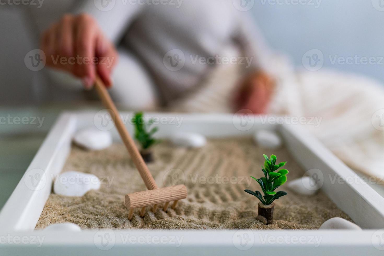 hand av skön ung kvinna använder sig av henne zen trädgård på Hem. härlig ung leende kvinna avkopplande med henne zen trädgård och njuter henne dag foto