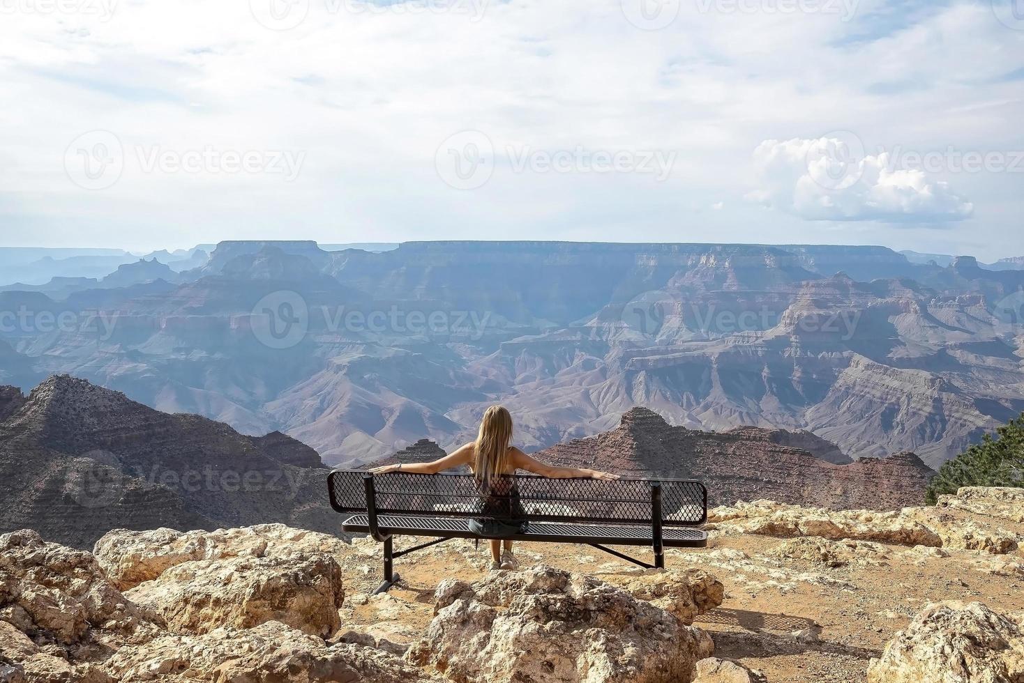 kvinna ser på stor kanjon medan Sammanträde på bänk foto
