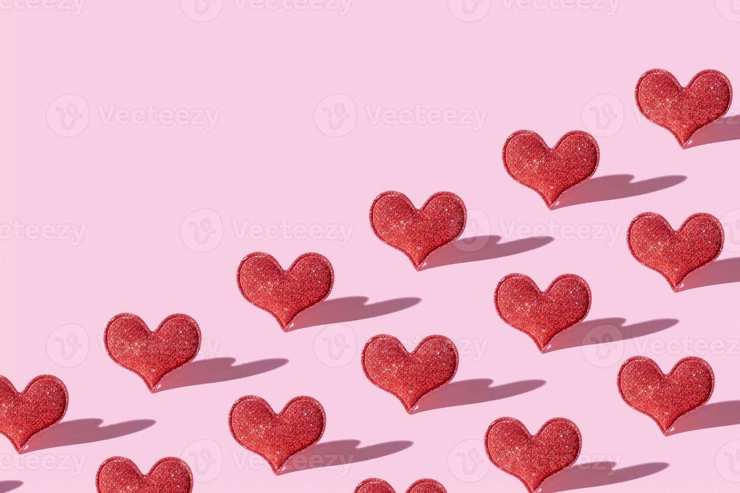 mönster med röd glitter hjärta form på rosa bakgrund med hård skugga. valentines dag minimalistisk symbol kärlek foto