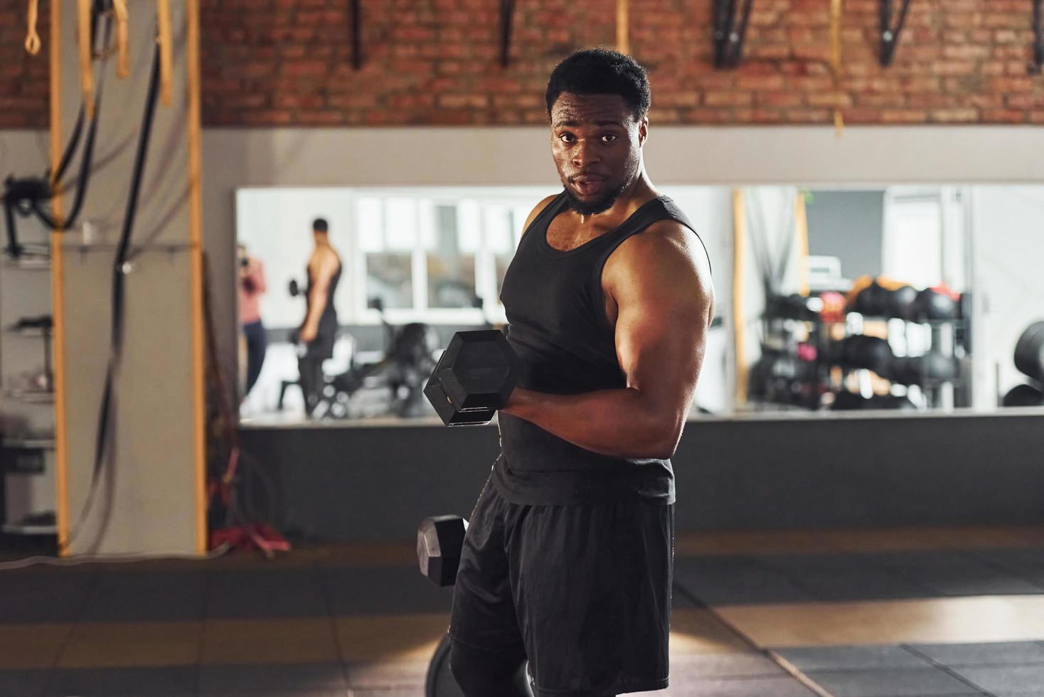 stark afrikansk amerikan man i sportigt kläder lyft hantlar i de Gym foto