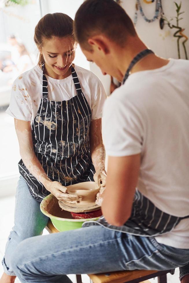 med henne pojkvän eller Make. ung kvinna keramiker inomhus med handgjort lera produkt. uppfattning av krukmakeri foto