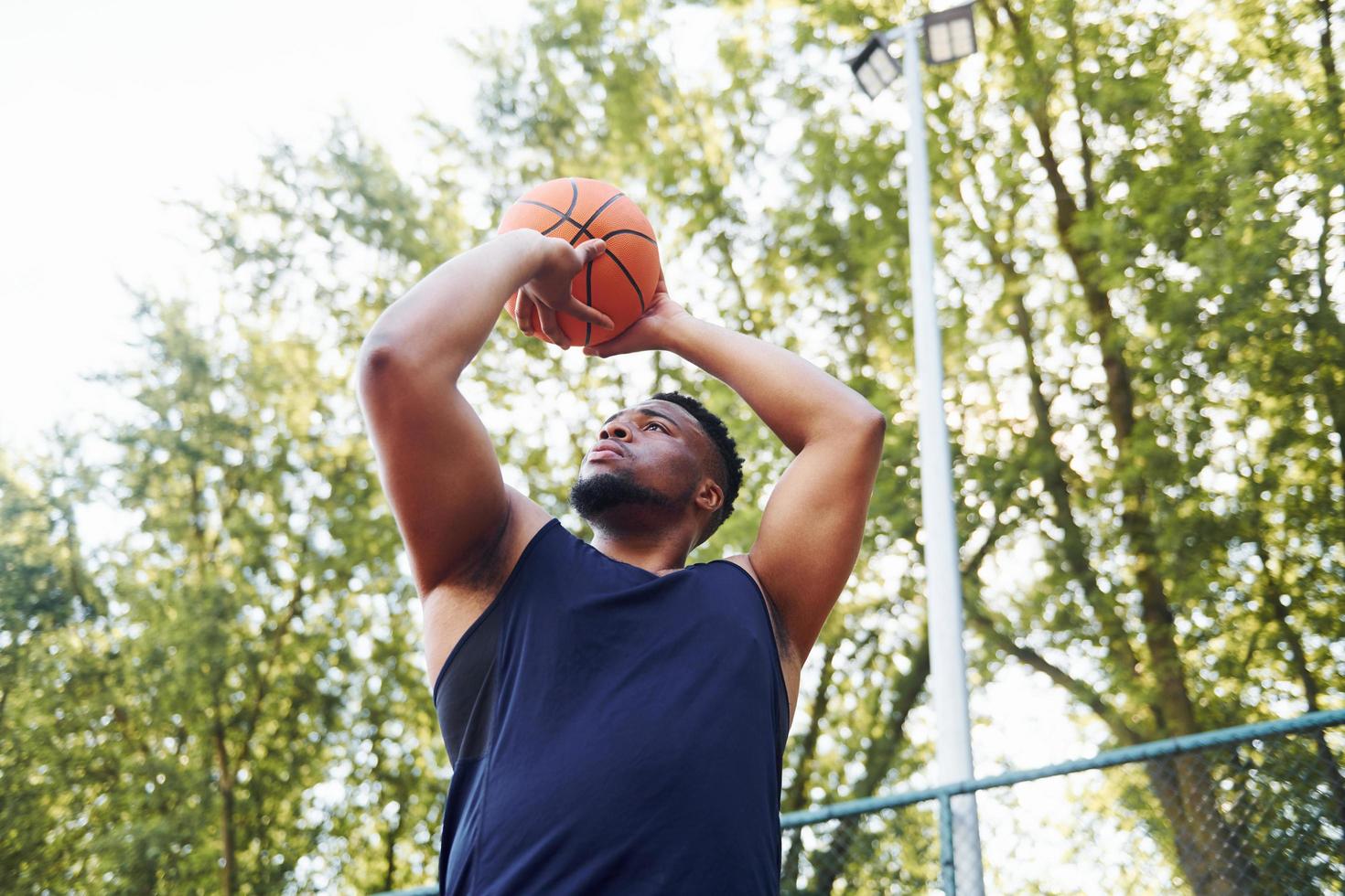 molnig väder. afrikansk amerikan man spelar basketboll på de domstol utomhus foto