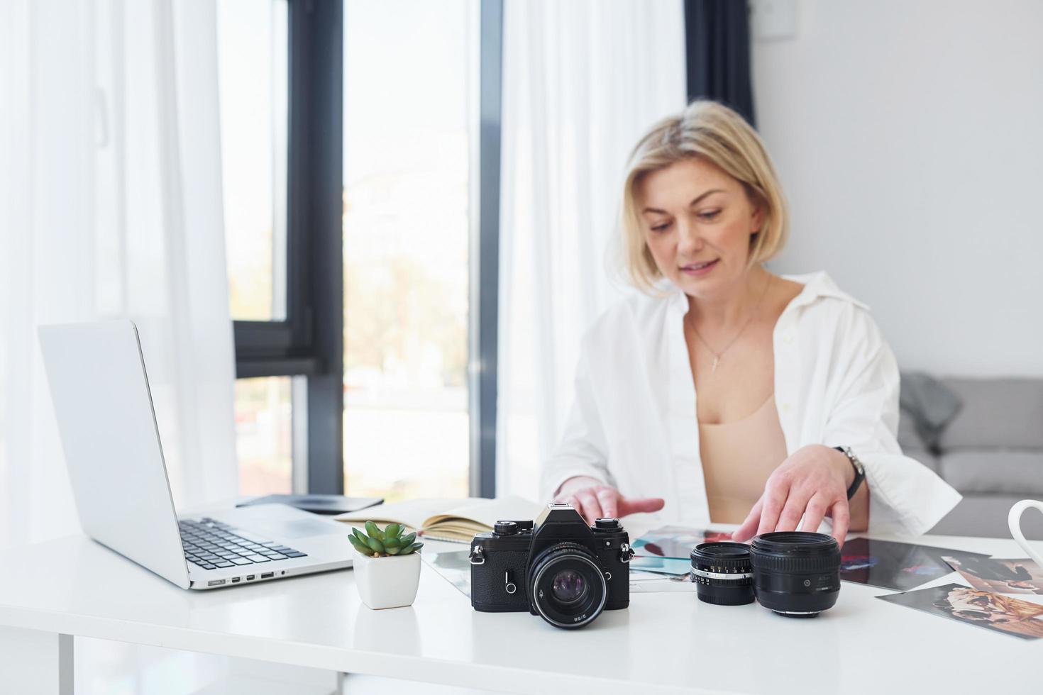 medelålders kvinna i elegant kläder är på Hem. fotograf med kamera foto