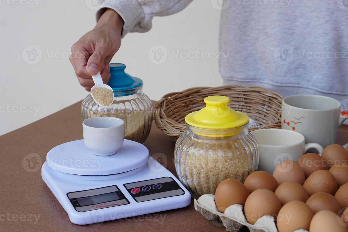 närbild hand skalor socker för matlagning, förbereder ägg och Övrig mat Ingredienser för göra småkakor. begrepp, matlagning , bageri. kärlek matlagning livsstil. tidsfördriv aktivitet. kök foto