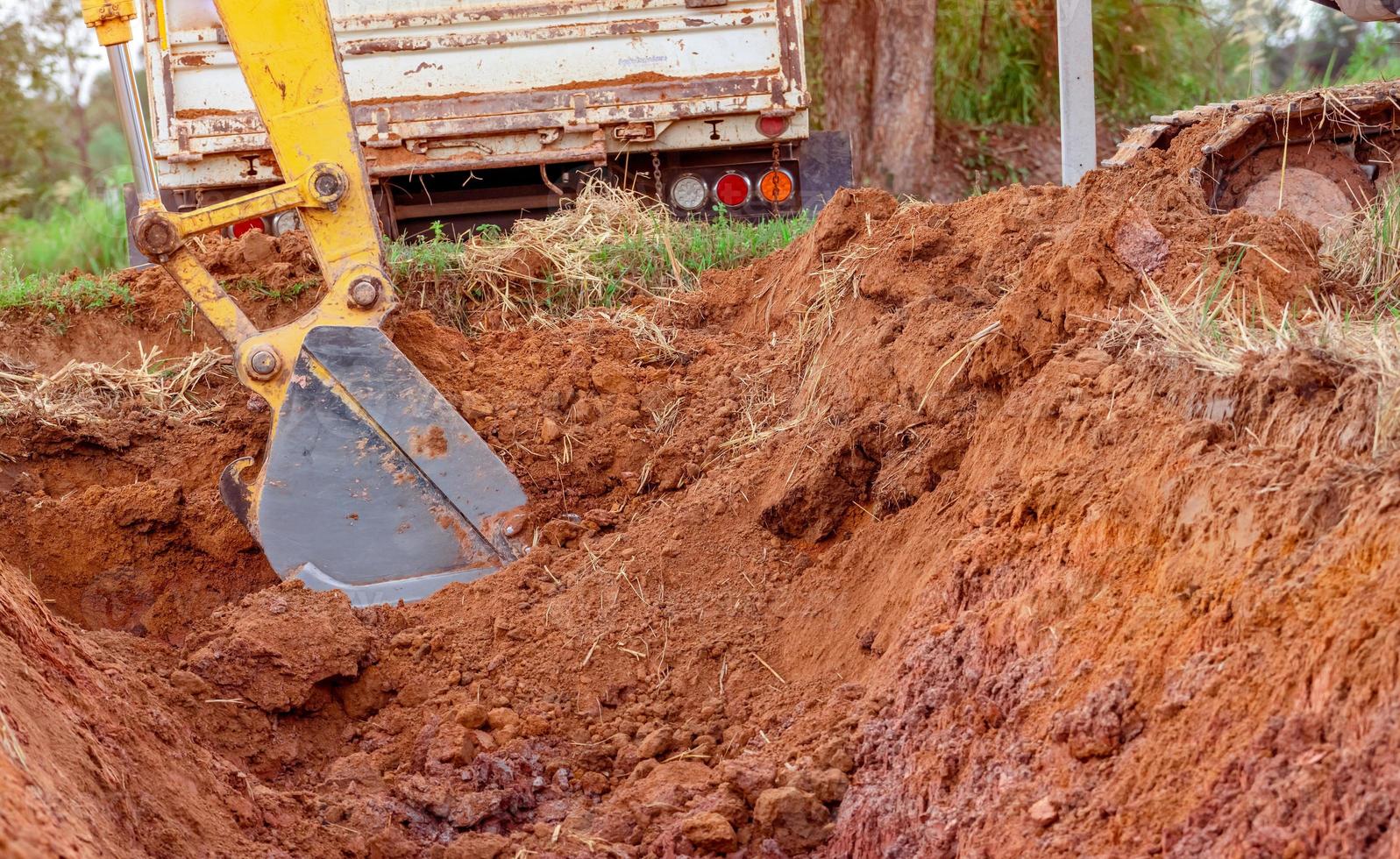 grävmaskin hink grävning jord för läser in till lastbil. schaktning. smuts metall hink av traktor arbetssätt på en konstruktion webbplats. schaktning maskin. jord utgrävning. grävmaskin grävning på rivning webbplats. foto