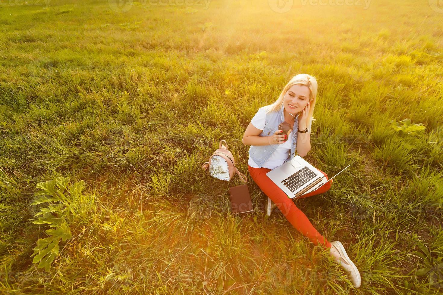 ung kvinna med bärbar dator Sammanträde på grön gräs foto