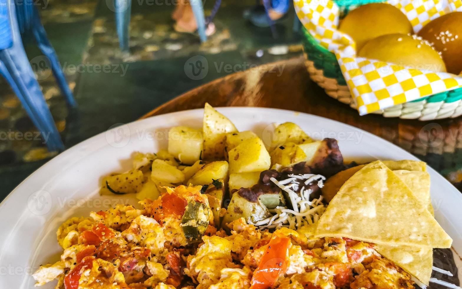 mexikansk omelett ägg svart bönor potatisar nachos på vit tallrik. foto