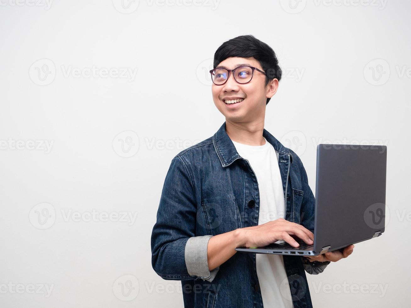 ung affärsman jeans skjorta mild leende använder sig av bärbar dator sväng ansikte ser kopia Plats foto