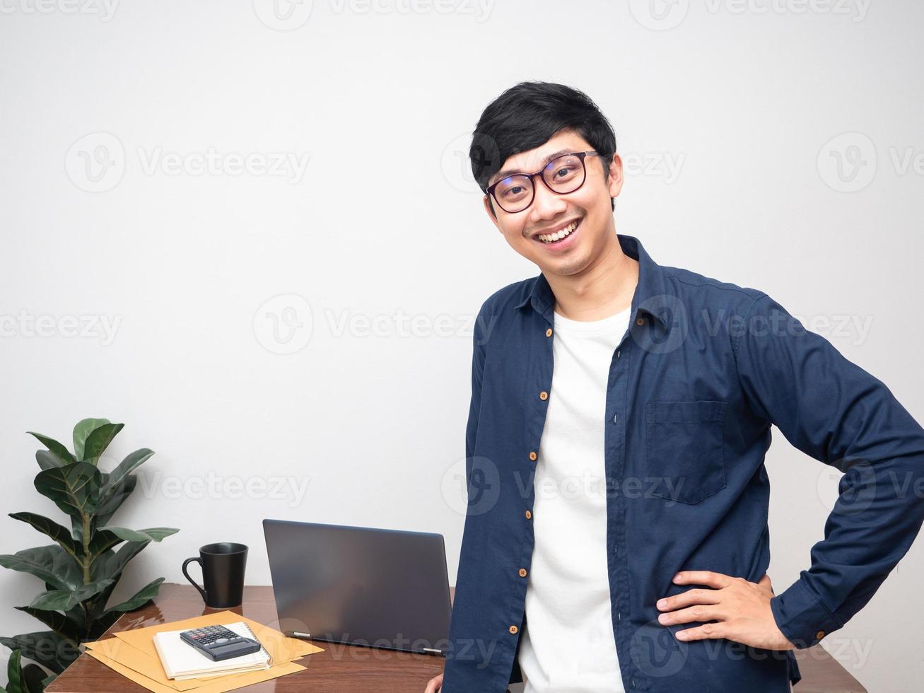 positiv man bär glasögon gest hand på midja Lycklig leende på hans arbetssätt tabell kopia Plats foto