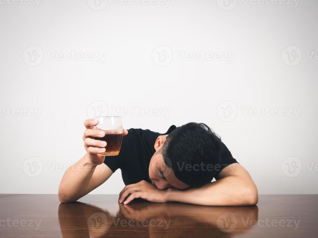 man alkoholism baksmälla om på tabell och håll alkohol glas i hand foto