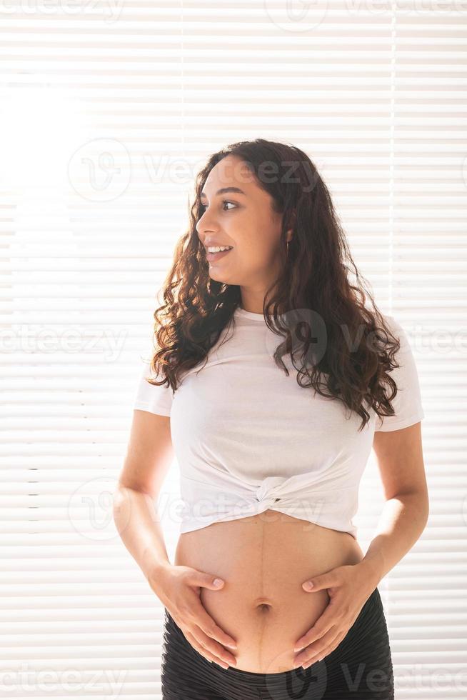gravid kvinna rörande henne mage. graviditet och moderskap lämna foto