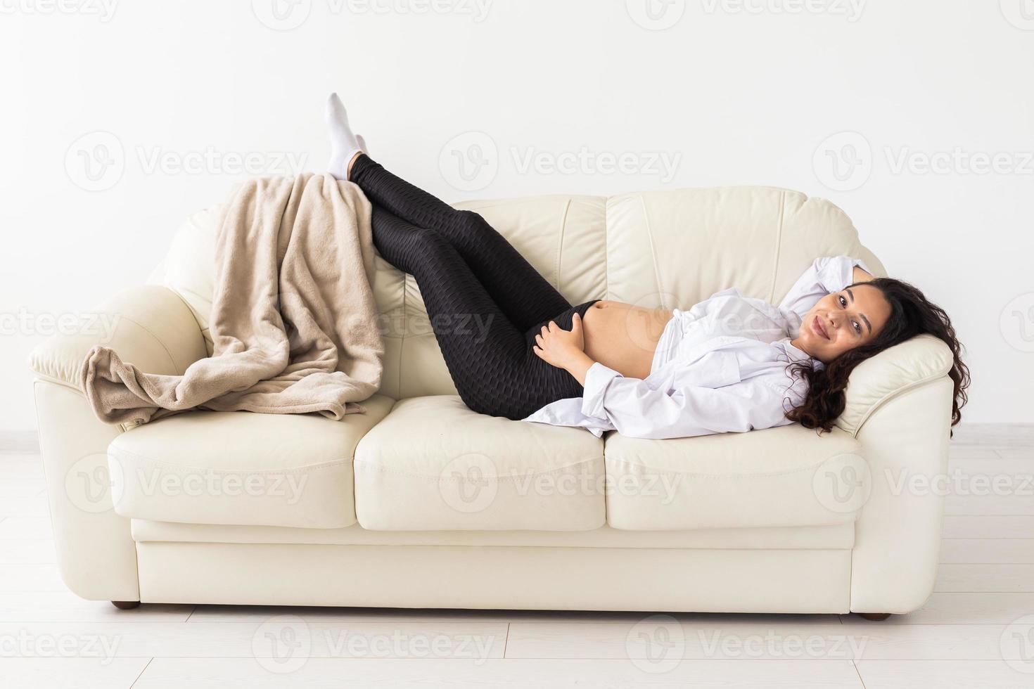latinamerikan gravid kvinna liggande på soffa på Hem. graviditet, vilar och förväntan begrepp. foto
